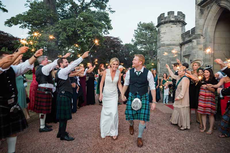 Sparklers and bride and groom outside Winton Castle with wedding guests
